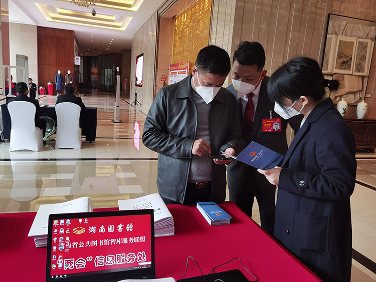 湖南省十四届人大一次会议期间，工作人员协助代表根据宣传册安装并使用app